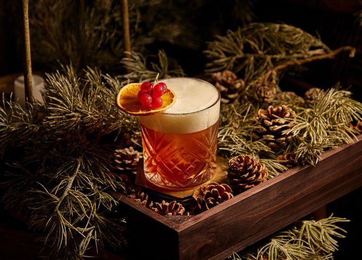  An orange cocktail with white froth and a dehydrated orange wheel garnish.