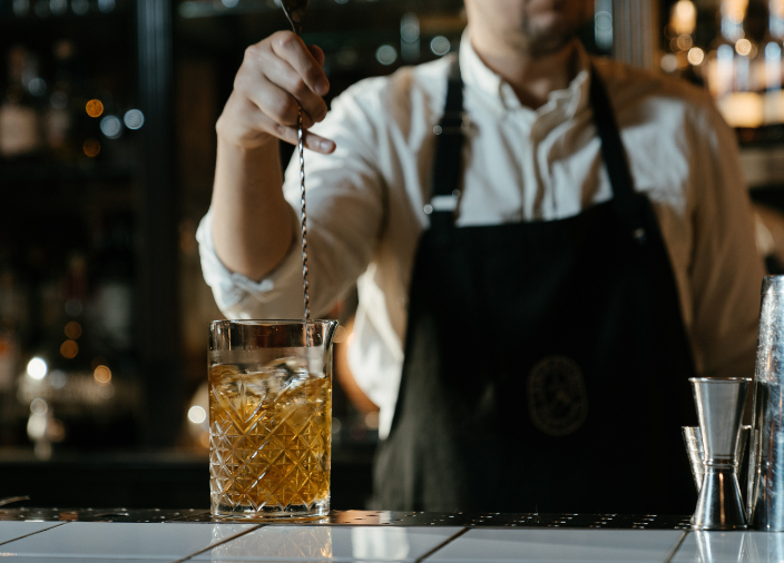 Una mano mezclando un líquido en un vaso con una cuchara