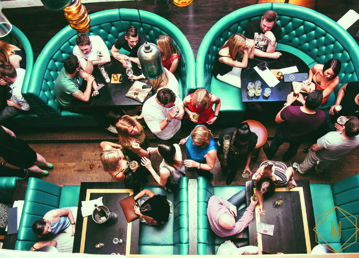 Birdseye view of bar booths with people seated and standing 