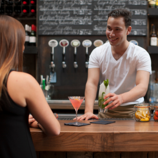  Bartender serving customer an orange cocktail. 