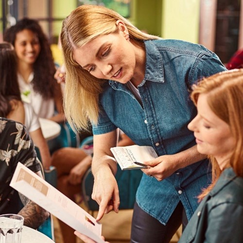 Waitress pointing out something on a menu to a customer