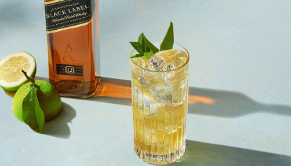 Johnnie Walker Lemon Highball served in a Highball glass with garnish & bottle of Johnnie Walker Black Label 