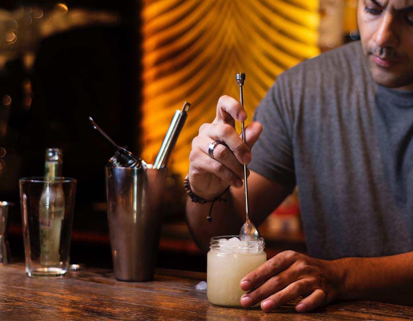 A person stirring a cocktail with a long-stemmed stirring spoon.