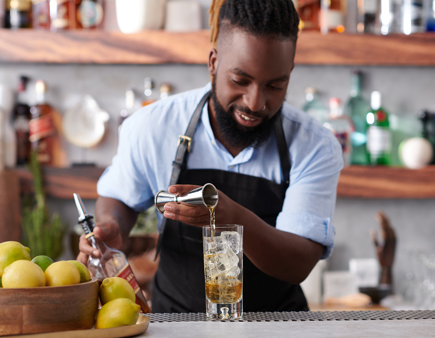 bartender behind bar pouring spirit into glass