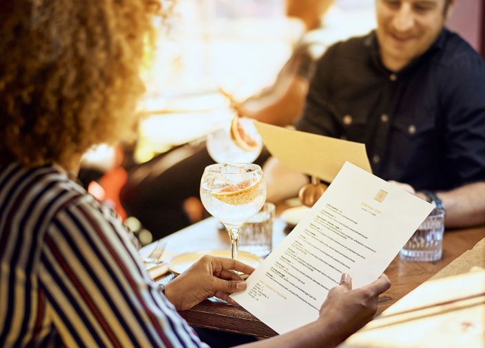 Zwei Personen sitzen an einem Tisch und lesen Speisekarten