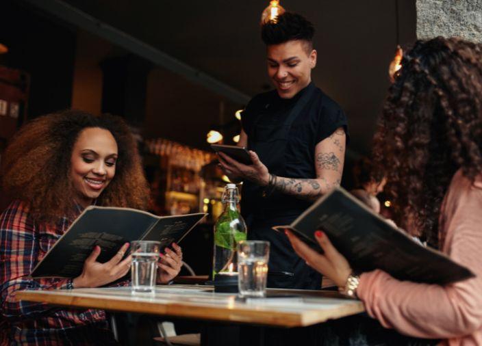 female staff taking customers orders at table