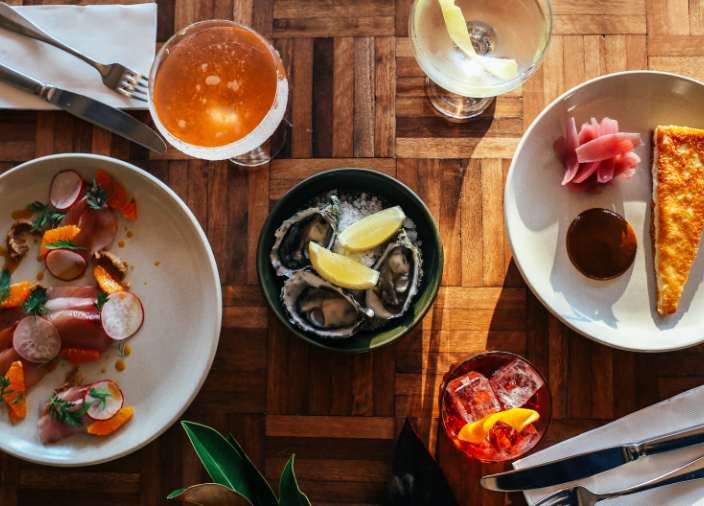 Birdseye view of table with plates of food, cocktails and cutlery