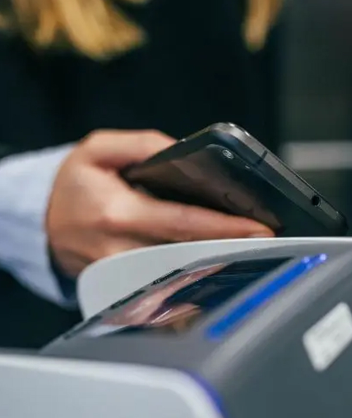 Woman taps to pay with her phone at a POS terminal.