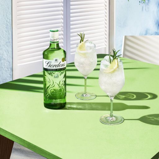 Gordons bottle accompanied by two garnished cocktails.