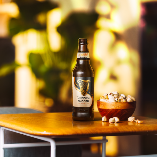 Eine Flasche Guinness Smooth steht auf dem Tisch neben einer Schüssel Popcorn