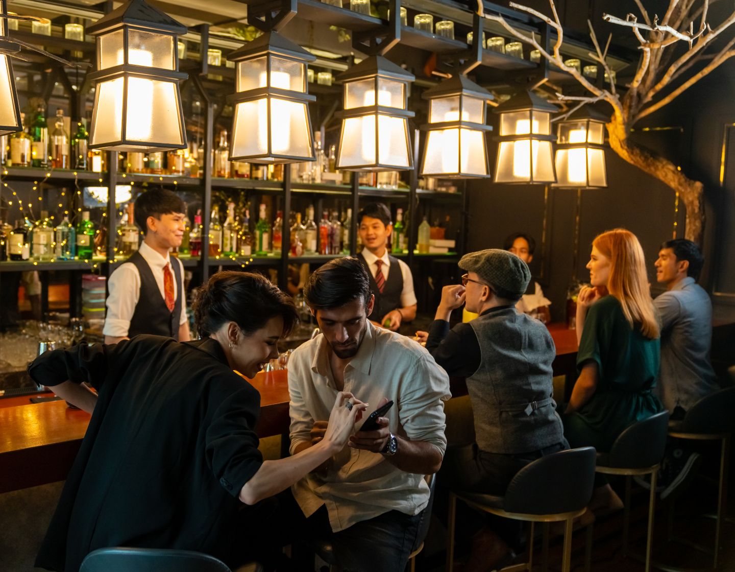 Bar ocupado con dos bartenders que atienden a los clientes.