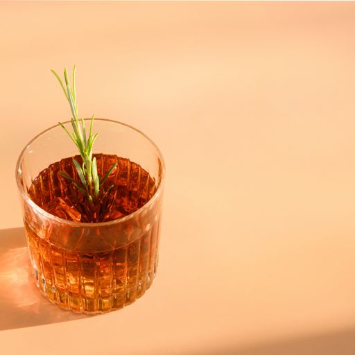 Vaso de Whisky con hielo y guarnición de romero