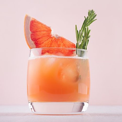 Cocktail auf rosa Hintergrund mit orangefarbener Garnierung