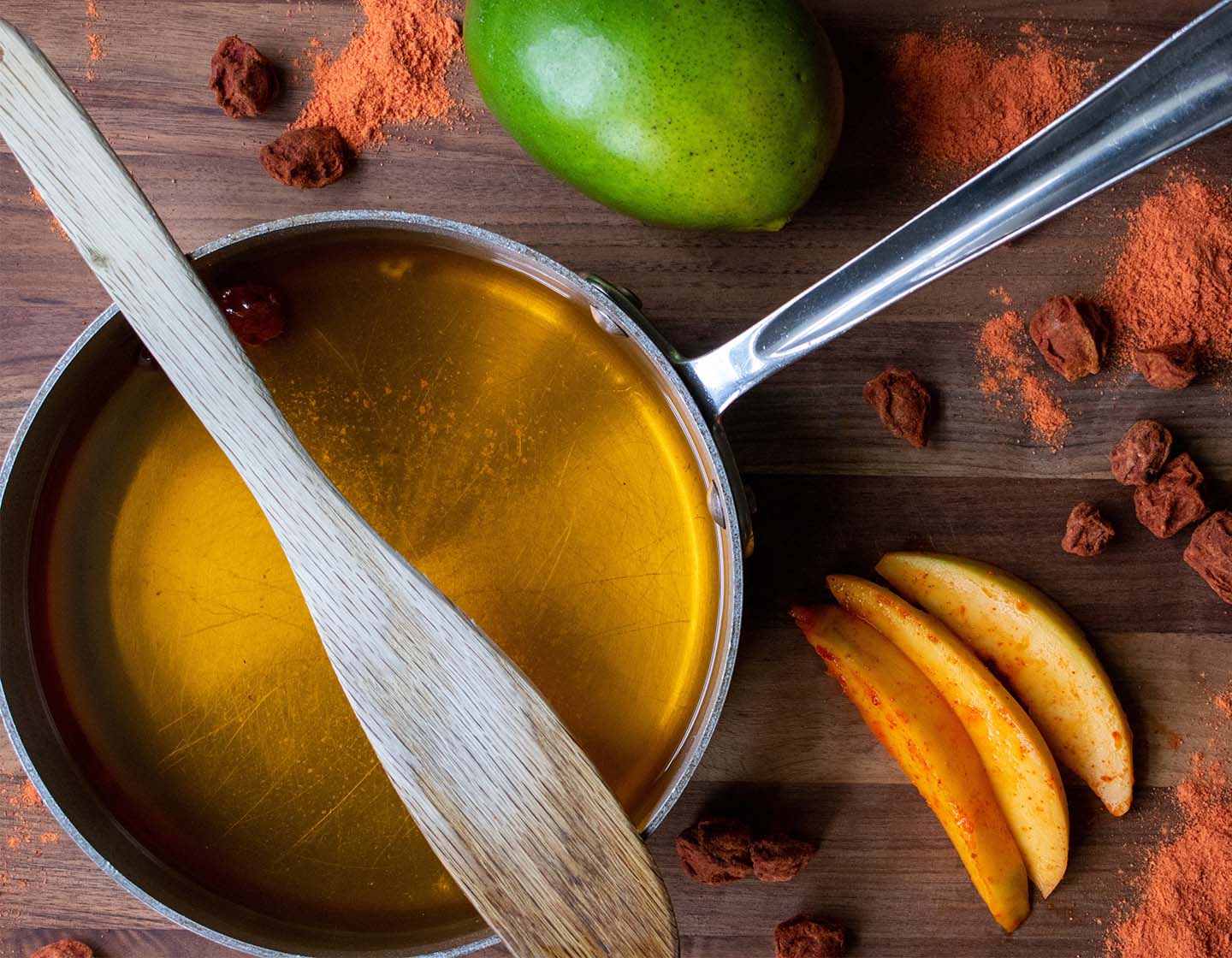 Cazuela con almíbar rodeada de especias y mango.