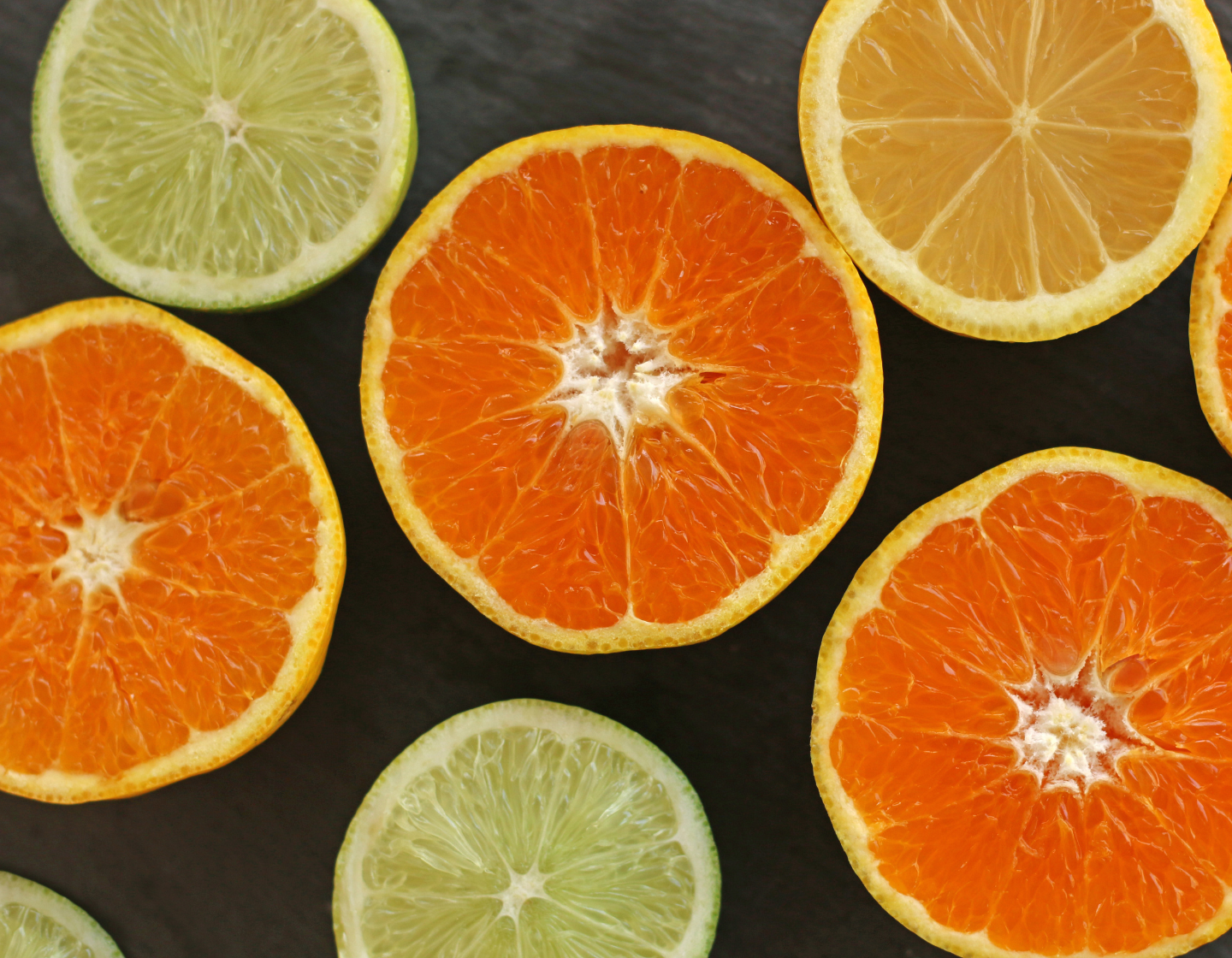 Metades de frutas cítricas variadas sobre fundo escuro