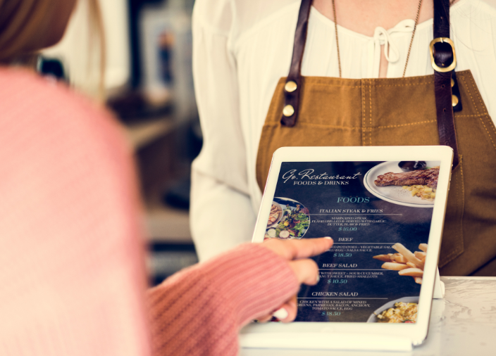Imagem de um bartender mostrando um menu digital para o cliente