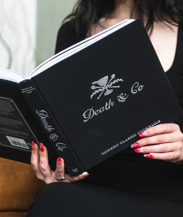 Black book called "Death & Co Modern Classic Cocktails" held in hands