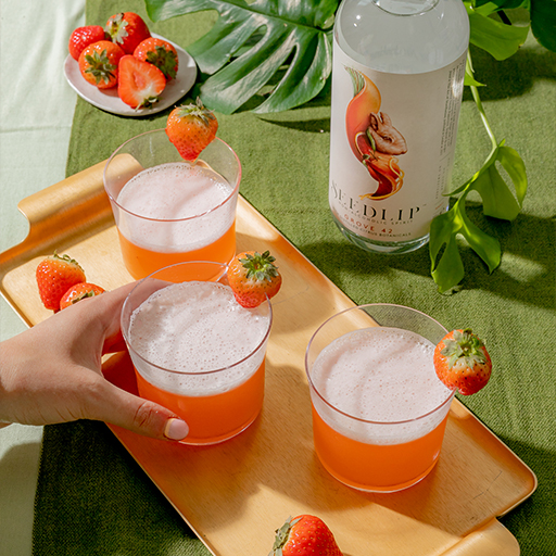 Three alcohol free orange coloured cocktails with Seedlip bottle