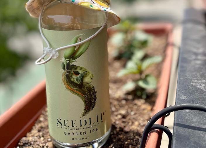 A bottle of Seedlip in a wheelbarrow filled with soil 