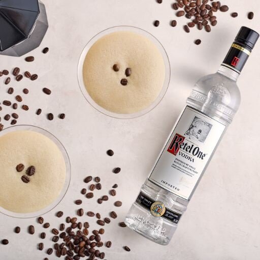 Zwei Espresso-Martinis aus der Vogelperspektive, neben einer Flasche Ketel One Wodka, umgeben von Kaffeebohnen.