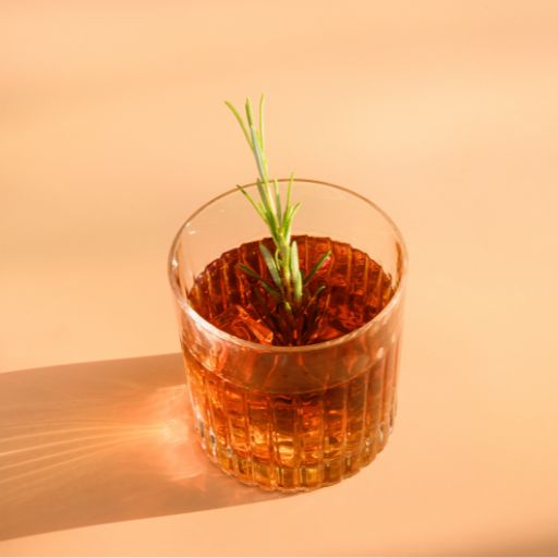Whiskey cocktail garnished with sprig.