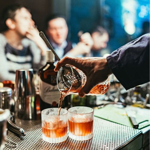 Two cocktails being strained from a shaker into glasses 