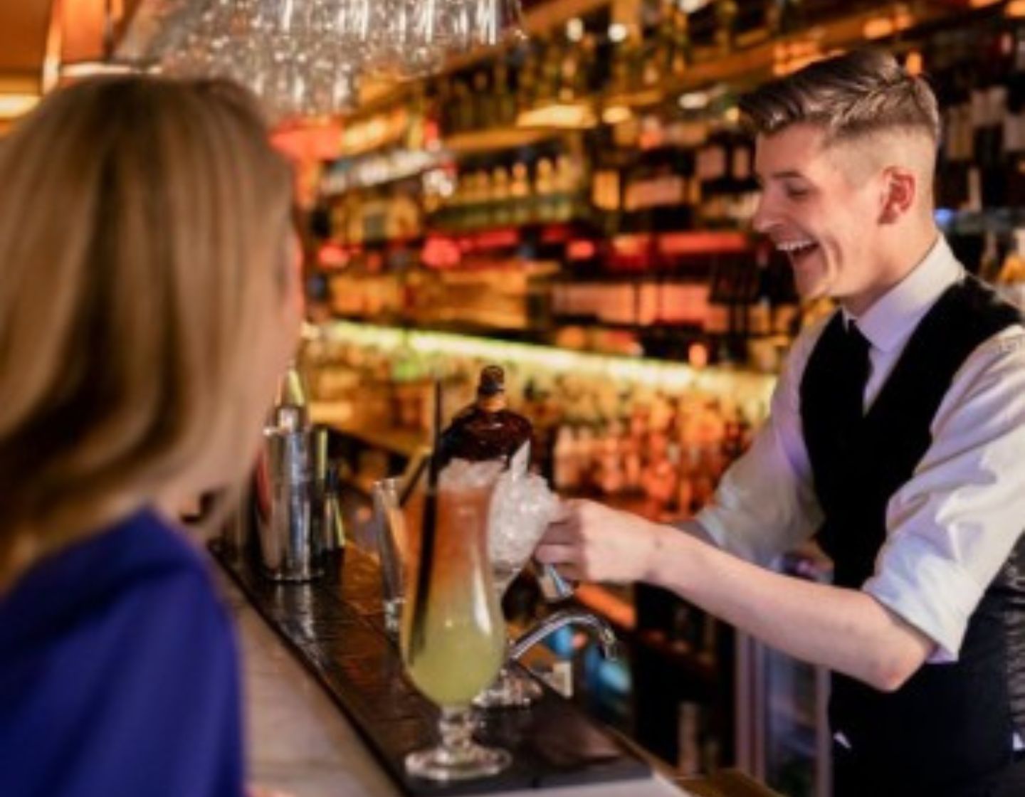 Bartender serving a customer a yellow cocktail