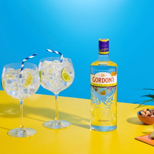Fila de diferentes botellas de ginebra Gordon's contra un fondo colorido 
