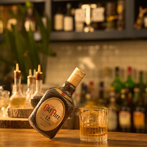 Bottle of Old Parr on table with cocktails