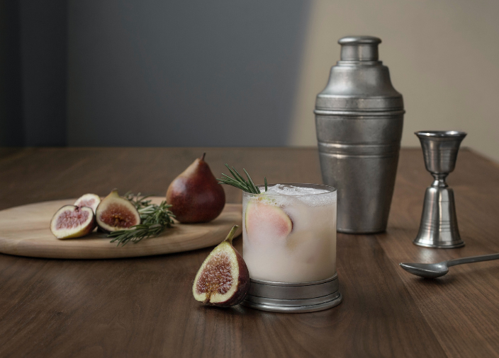 Cocktail shaker, jigger and spoon beside cocktail 
