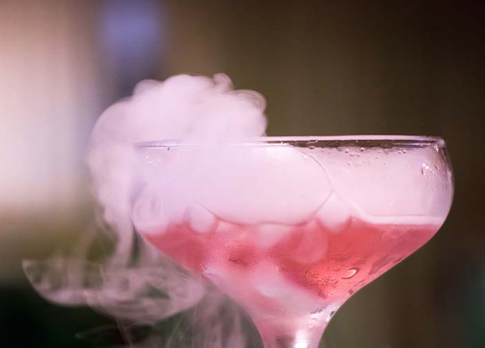 Nahaufnahme eines mit Flüssigkeit und Nebel/Rauch gefüllten Cocktailglases.