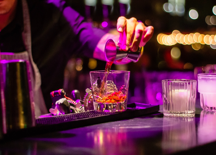 Hand pouring a drink measure at a bar