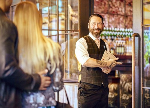 Bartender recibiendo a los clientes en la puerta 