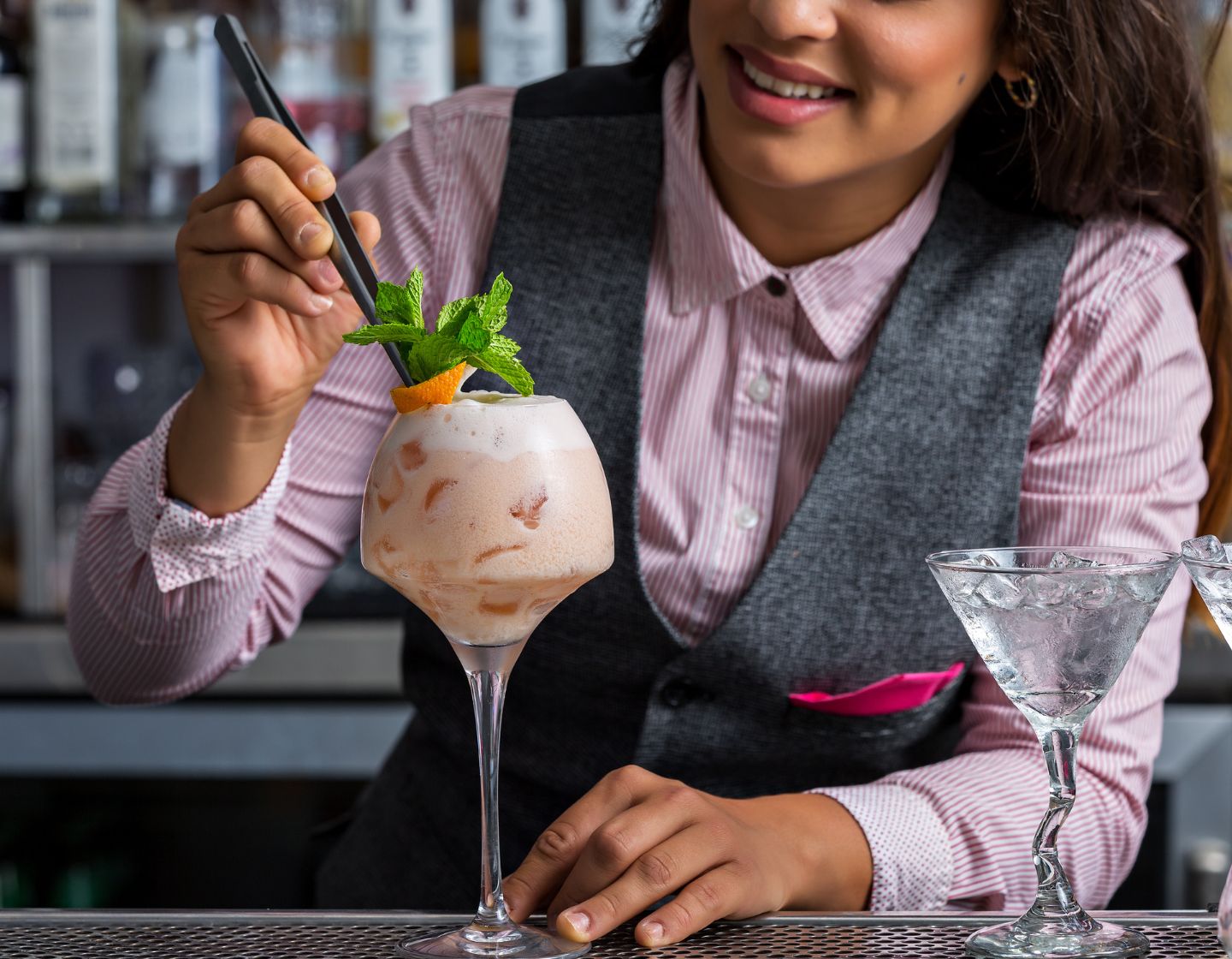 Bartender adding garnish with tongs 