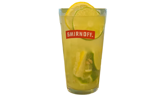 Copo alto com logo vermelho da Smirnoff contendo um coquetel refrescante amarelo-claro. A bebida leva muito gelo e fatias de limão verde e limão siciliano, tanto misturadas no interior quanto decorando o topo. Fundo branco.