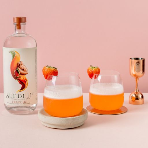  Seedlip Grove 42 con fondo rosado y dos cócteles adornados con fresas