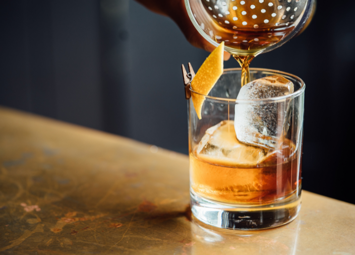 Bartender colocando una cáscara de limón en un highball