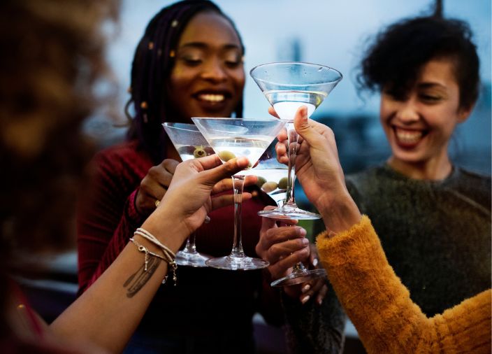 Vier Freunde lächeln und stoßen mit vier Martini-Cocktails an.