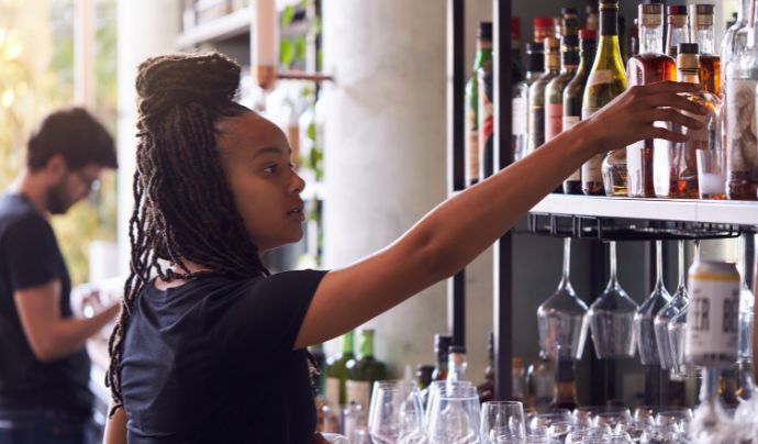 Bar staff lifting a bottle from a shelf