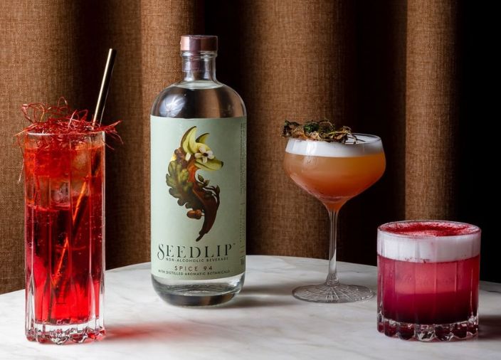 Botella de Seedlip junto a tres cócteles expertos sin alcohol