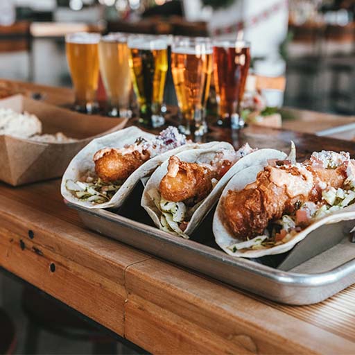 Imagen de tacos en la parte superior de un bar con bebidas al fondo.