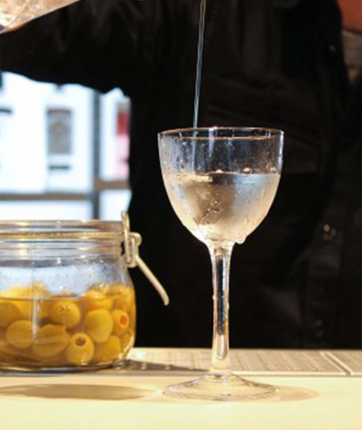 Bartender straining muddled olives. 