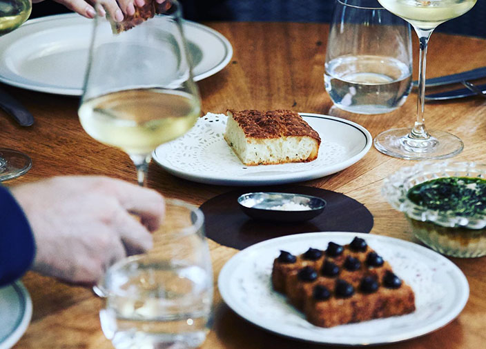 People eating at a table with food and wine