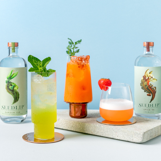 Three colourful cocktails surrounded by three different bottles of Seedlip non-alcoholic spirits. 