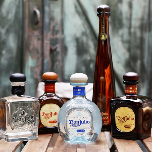 Selección de diferentes botellas de tequila Don Julio colocadas sobre una mesa de madera 