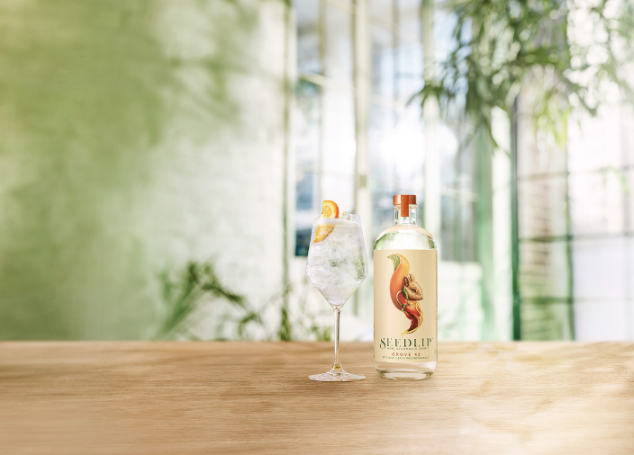 Eine Flasche Seedlip Grove 42 auf dem Tisch neben dem Cocktail