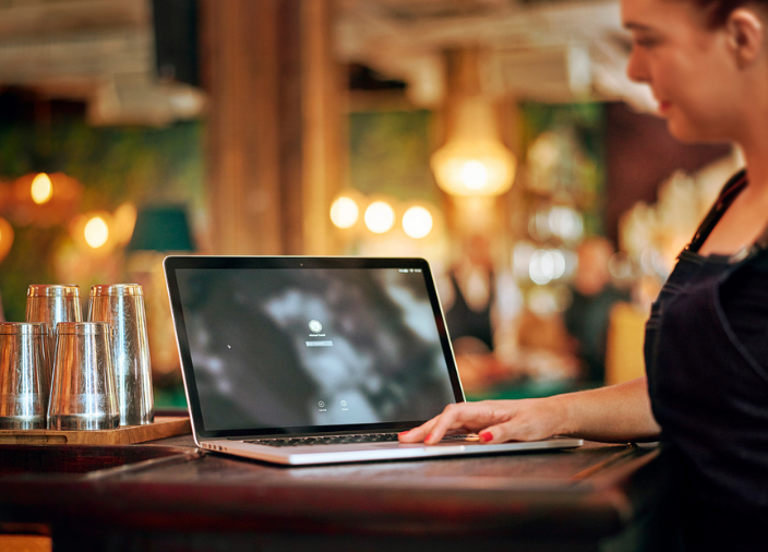 Bar staff member using laptop at the bar 