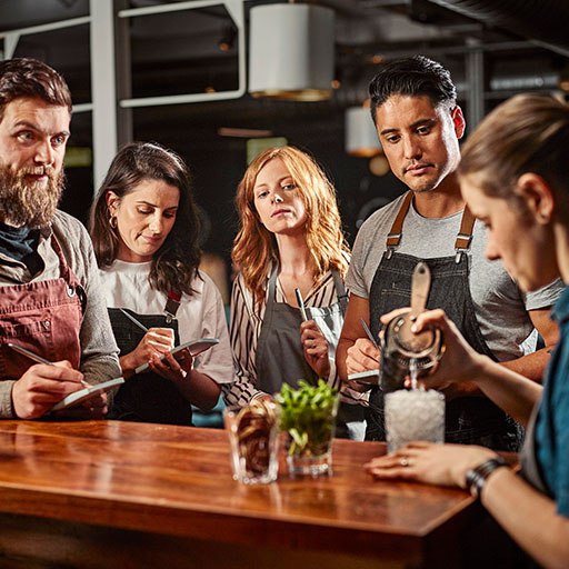 Bartenders tomando notas, viendo cómo se prepara un cóctel