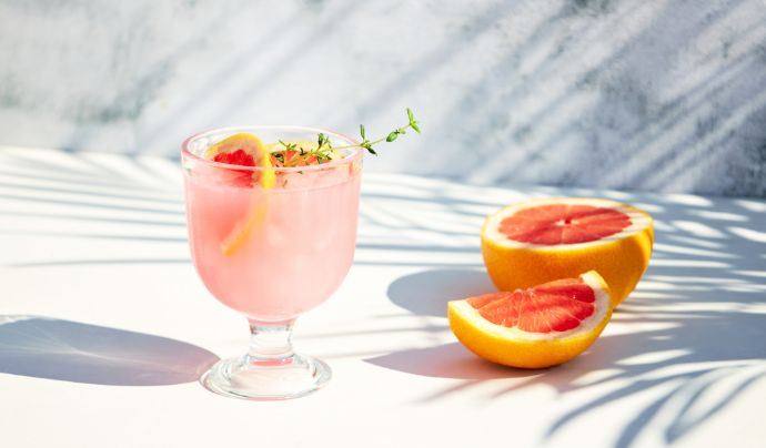 Fatia de grapefruit num coquetel com uma garrafa Tanqueray No. Ten ao fundo 