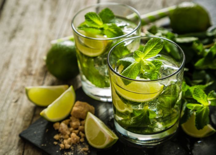 Dos cócteles de Mojito en vaso tupo tumbler con adorno de menta y lima